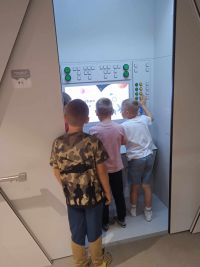 08. Trzech chłopców stoi przed ekranem.