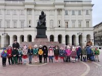 17. Dzieci z opiekunami po wyjściu z koncertu pozują do zdjęcia  przy  pomniku M. Kopernika