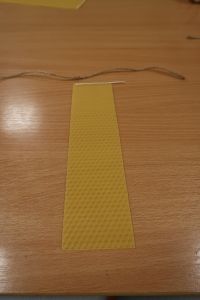 14. Plaster wosku z przeklejonym knotem leży na stoliku, obok szary sznureczek