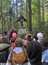 1 Dzieci i przewodniczka stoją przy tablicy informacyjnej przed wejściem na szlak