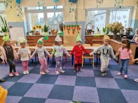 7. Dzieci w warzywnych czapkach maszerują w kole z piosenką ,,Idą witaminki''.