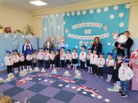 12. Pasowanie na przedszkolaka - Dzieci z Paniami i rodzic z dzieckiem na ręku pozują do pamiątkowego zdjęcia.