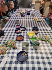 8. Warsztaty świąteczne - dzieci przy stolikach podziwiają swoje dzieła sztuki