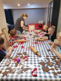 10. Warsztaty świąteczne - dzieci przy stolikach wycinają foremkami świąteczne pierniczki.