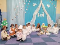 18. Jasełka - dzieci w kostiumach siedzą i pozują rodzicom do zdjęcia.