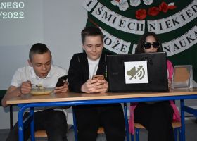 12. Troje uczniów siedzi przed komputerem, zupą, lusterkiem i telefonem.
