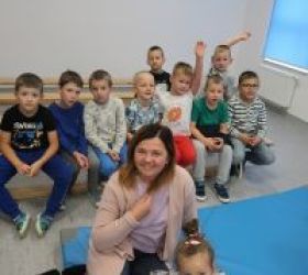 nauczycielka z dziećmi siedzą na  materacach i się uśmiechają